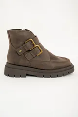 Botas cortas de cuero color visón con suela track, cierre lateral y doble tira con hebillas doradas.