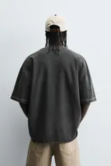 Camiseta color caqui de corte holgado, con cuello redondo y mangas cortas. Acabado con efecto lavado y ruedo irregular.