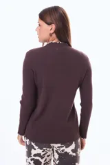 Buzo de tejido de punto acanalado en color beige, con cuello alto y terminaciones con borde ondulado en contraste negro en cuello y puños.