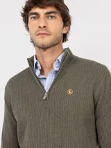 Sweater de punto acanalado en color azul marino, con cuello alto y cierre frontal parcial. Presenta mangas largas con puños acanalados y un pequeño logo bordado en rojo en el pecho.