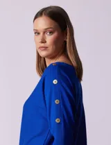 Buzo tejido color salmón de hilado fino, marca Cable & Gauge. Escote redondo con calados. Manga ¾, modelo dolman con aplique de botones dorados.