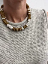 Pulsera de cuentas de madera color verde oliva y cuentas blancas, con cierre de gancho plateado.