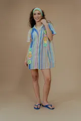 Vestido corto tejido a rayas verticales de colores pastel, con cuello camisero, cierre frontal con botones y bordado de flores de crochet.
