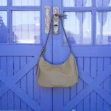 Cartera tipo hobo o media luna de cuero sintético negro, con textura granulada. Posee una correa ajustable para llevar al hombro o cruzada.