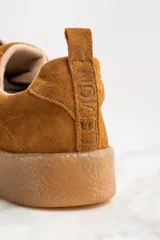 Zapatillas bajas de gamuza color marrón con apliques de estrellas doradas.