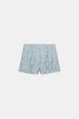 Shorts de tiro alto confeccionados en encaje con diseño floral. Presentan bolsillos delanteros y cierre frontal con cremallera y gancho metálico.