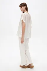 Blusa de algodón blanca de corte holgado, con cuello redondo y detalles de broderie en las mangas y costuras frontales.