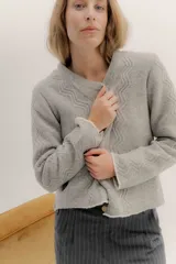 Saco tejido de lana con diseño de ochos y aranes en el frente. Presenta cierre frontal con ganchos peleteros, cuello redondo y pin bordado de la marca en la parte inferior.