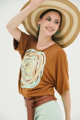 Remera color marrón con aplique textil en forma de espiral con cintas de colores pastel.