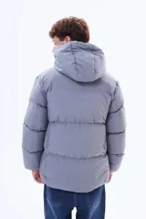 Campera puffer negra con capucha, cierre frontal y puños elásticos. Diseño acolchado con relleno térmico y exterior de nylon resistente.