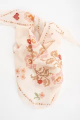 Bandana de algodón color crudo con diseño bordado en punto cruz que incluye motivos florales, corazones y conejos.