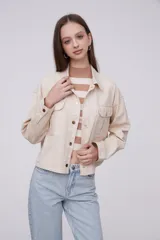 Chaqueta de algodón color beige, con diseño holgado, cuello tipo camisa, cierre frontal con botones metálicos y bolsillos frontales con solapa.