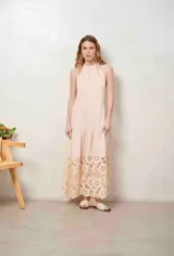 Vestido largo beige con cuello halter y detalle de broderie calado en el dobladillo inferior.
