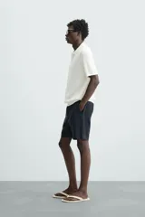 Bermuda azul marino de corte regular fit, confeccionada en tejido de algodón y lino. Cuenta con bolsillos frontales y traseros, cierre frontal con cremallera y botón.