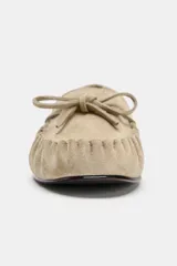 Mocasín plano de serraje color beige, con detalle de fruncido y lazo en la parte delantera y punta redonda.