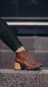 Botineta de cuero marrón con taco ancho efecto madera, plataforma sutil y detalles de elástico texturizado en los laterales.