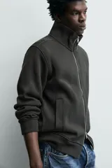 Chaqueta regular fit confeccionada en tejido interlock de algodón con elasticidad. Presenta cuello subido, manga larga, bolsillos de vivo en la cadera, acabados en rib y cierre frontal con cremallera.