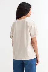 Remera de manga corta color beige, con estampa frontal en tono azul con la leyenda "New York 1990", de corte holgado y diseño casual.