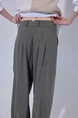 Pantalón tipo bombachita con pinzas que aportan volumen, confeccionado en Tencel. Presenta cierre frontal con botones dorados, bolsillos delanteros y ruedo ajustable mediante botón dorado.