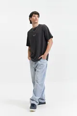 Remera de manga corta color gris oscuro, con escote redondo y ajuste regular. Presenta un estampado frontal con el texto "MISTRAL KAMIOKA NEW TRIAL SINCE 1976 // NLD".