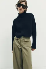 Pantalón culotte de tiro alto en color verde militar. Presenta bolsillos frontales de plastrón con solapa, cierre frontal con cremallera y botón, y diseño de pierna ancha con dobladillo marcado.