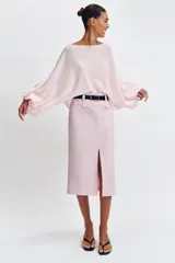 Falda midi tubo de color rosado con abertura frontal en el bajo y cierre lateral con cremallera oculta. Incluye un cinturón negro con hebilla dorada.