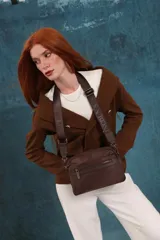 Bandolera de diseño moderno y funcional, confeccionada en nylon color marrón claro. Cuenta con múltiples compartimentos con cierre metálico, herrajes plateados y una correa ancha ajustable con detalle de marca.