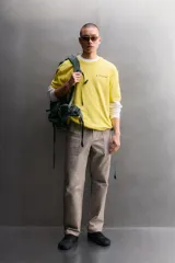 Camiseta de corte relaxed fit color amarillo, confeccionada en tejido compacto de algodón, con cuello redondo, manga corta y estampado frontal a contraste con texto y motivo floral pequeño.