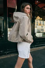 Cazadora con capucha ajustable, manga larga con puños elásticos, bolsillos delanteros y bajo ajustable con cordones. Cierre frontal con cremallera y diseño estampado a cuadros.