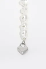 Pulsera elástica compuesta por perlas irregulares de color blanco y un dije metálico en forma de corazón con cierre tipo candado.