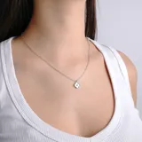 Collar de cadena fina plateada con dije en forma de trébol de cuatro hojas, con centro de cristal y borde dorado.