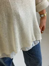 Sweater de punto color beige, de corte amplio y holgado, con escote redondo y mangas largas con presillas para arremangar.