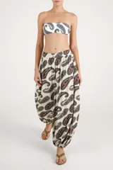 Pantalón de corte fluido color beige con estampado paisley en tonos oscuros, tiro alto con lazo para anudar en la cintura y botamangas con elástico.