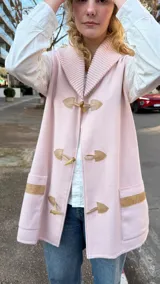Chaleco de lana merino color rosa pastel, con cuello tejido tipo chal, cierre frontal con botones tipo duffle y bolsillos laterales con detalle en tono contrastante.
