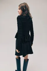 Top negro de manga larga en tejido fruncido con escote bote y detalles de volados en el diseño, corte entallado y peplum.