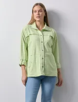 Camperita de mujer Ruby Rd. color verde lima con rayas blancas horizontales. Presenta cuello camisero, cierre frontal con botones metálicos a presión y bolsillos delanteros con solapa. Las mangas son largas y se pueden remangar.