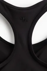 Top deportivo negro con espalda deportiva y soporte medio.