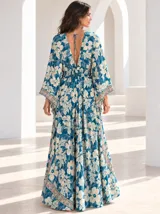 Vestido largo de estilo bohemio, color azul con estampado floral en tonos blancos y detalles geométricos en el escote y la cintura. Posee escote en V con cordones ajustables, mangas amplias tipo kimono y una silueta fluida y holgada.