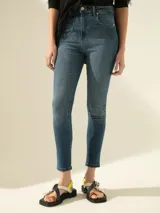 Jeans chupín de tiro medio-alto confeccionados en denim de algodón elastizado, con lavado medio y desgastes sutiles.