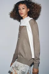 Jersey de punto fino en color marrón topo con escote en pico y manga larga. Presenta un diseño de doble capa con un bajo de encaje floral en color crudo que sobresale en la parte inferior.