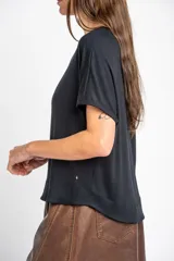 Remera negra de corte oversize, con mangas cortas y cuello redondo, confeccionada en tejido de viscosa y elastano de caída fluida.