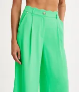 Pantalón recto de crepé color verde neón, con cintura alta acabada en forma ondulada. Prenda con trabillas, botón tipo escudo, bolsillos delanteros y traseros y detalle de pliegues delanteros.