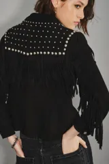 Camisa negra de gamuza caprina con cuello y hombros adornados con tachas metálicas plateadas. Presenta flecos decorativos en el canesú y botones plateados en el frente.