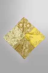 Bandana cuadrada confeccionada en tejido ligero de mezcla de ramio y algodón, con diseño de patchwork que combina paneles con estampados florales y paisley en tonos amarillo, mostaza y verde militar.