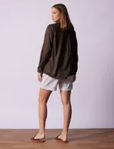 Camisa color verde oliva de lyocell, marca Cyrus. Tiene cuello con solapa, abertura central con botones, mangas 3/4 regulables con presilla y botón, y dos bolsillos delanteros aplicados.