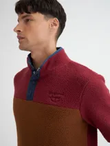 Buzo de polar color borgoña y marrón, con cuello alto con botones a presión y bolsillos laterales.