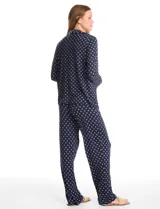 Conjunto de pijama de dos piezas con estampado animal print. La parte superior es una camisa de manga larga con cuello solapa, escote en V, cierre frontal con botones y bolsillo aplicado. El pantalón cuenta con cintura elástica y lazo de ajuste.