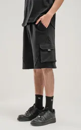 Bermuda negra de algodón rústico, corte oversize, con cintura elástica y bolsillos cargo con cierre en los laterales.
