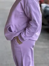Pantalón deportivo de tiro alto, color lavanda, con bolsillos laterales y puños elásticos en los tobillos.