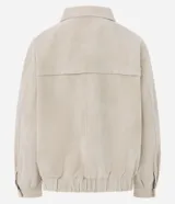 Campera bomber oversized de poliuretano con acabado efecto gamuza en color beige. Presenta cuello camisero, cierre frontal, mangas largas con puños abotonados y ruedo elástico.